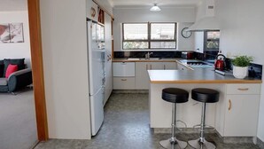 A compact kitchen with a central island, a refrigerator, a sink, and a window providing natural light.