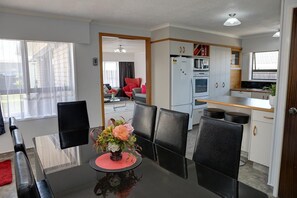 A compact living space with a dining area, kitchenette, and a view through a doorway.