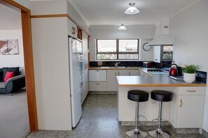A modern kitchen with a central island, bar stools, and a window providing natural light.