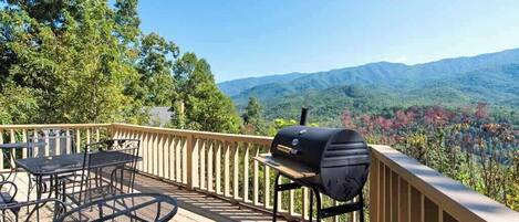 Una terraza con una parrilla y mobiliario exterior, con vistas a un paisaje montañoso.