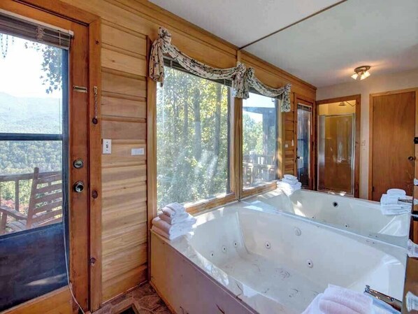 A wooden cabin with a large bathtub and a view of the forest. - Woodshed by Jackson Mountain Rentals (Gatlinburg)