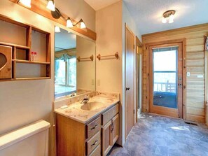 A bathroom with a marble sink, wooden cabinets, and a large mirror. - Woodshed by Jackson Mountain Rentals (Gatlinburg)