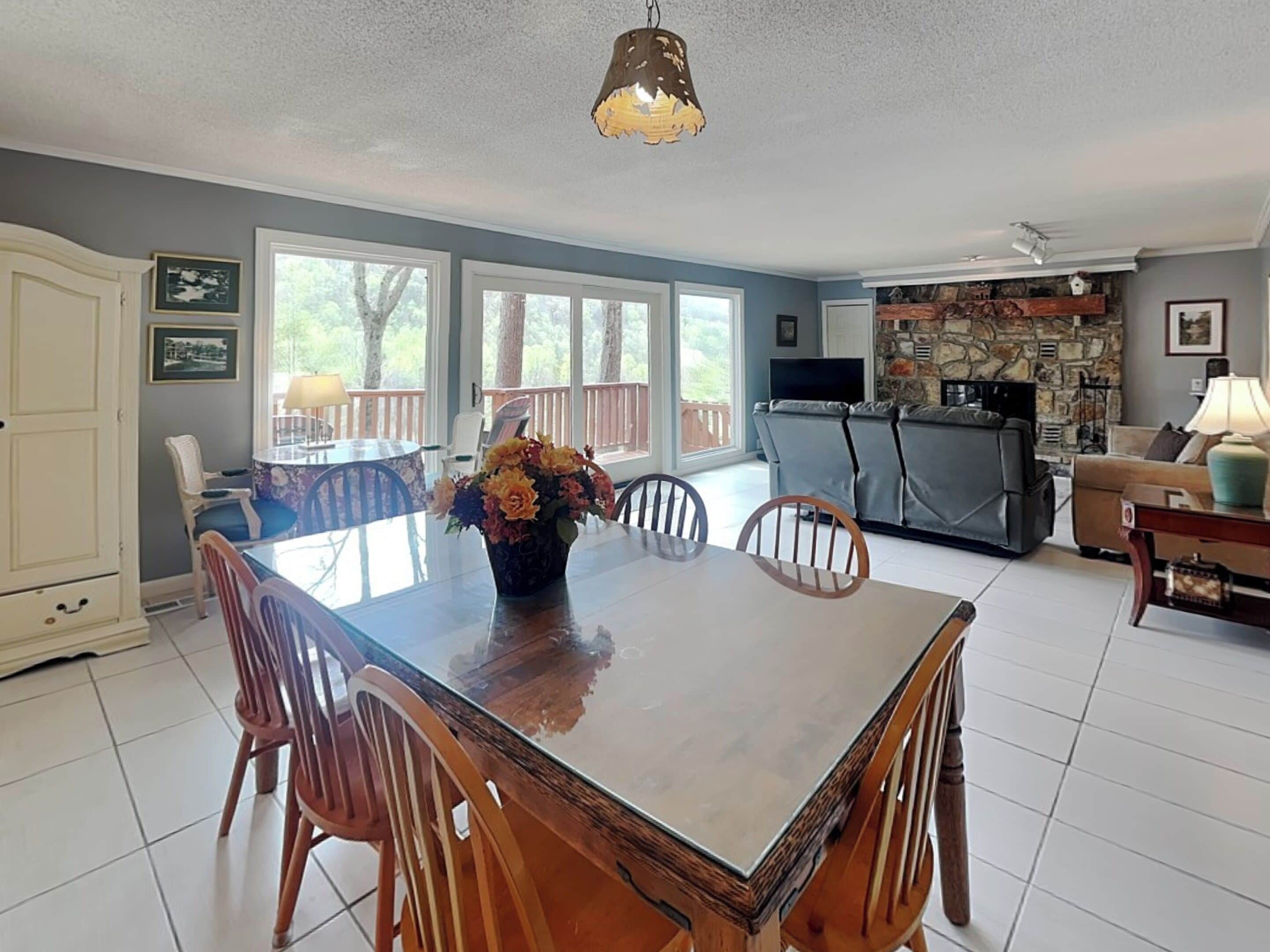 A dining area with a wooden table, chairs, and a vase of flowers.