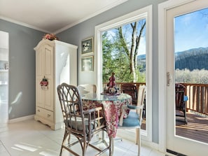 Enjoy meals in the dining area with a glass-top table and comfortable chairs, surrounded by a serene forest view.