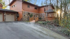A two-story house with a stone foundation, a wooden deck, and a garage. - Shooting Star by Jackson Mountain Rentals (Gatlinburg)