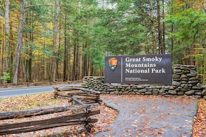 Enter the Great Smoky Mountains National Park through this scenic entrance, marked by a prominent sign and stone wall.