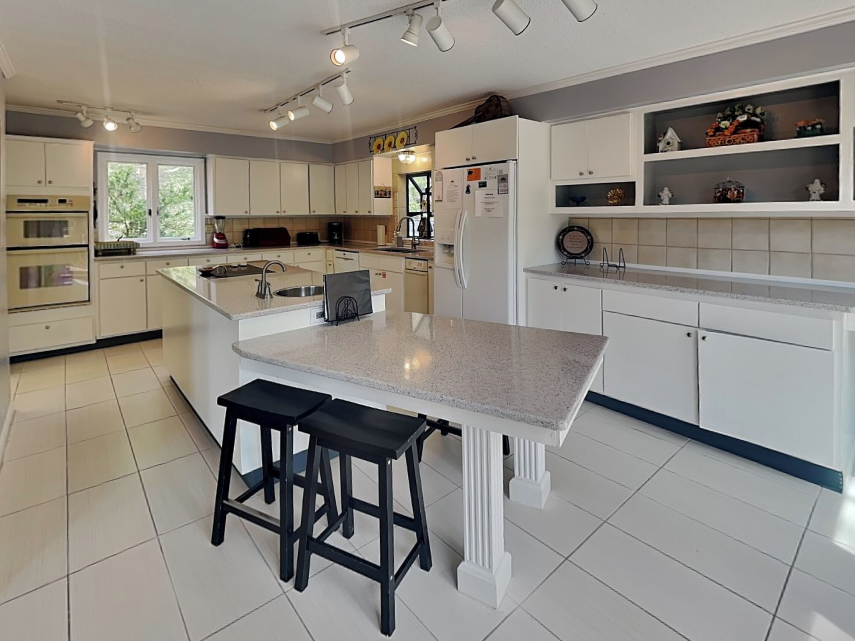 A modern kitchen with white cabinets, a granite countertop, and a central island with stools.