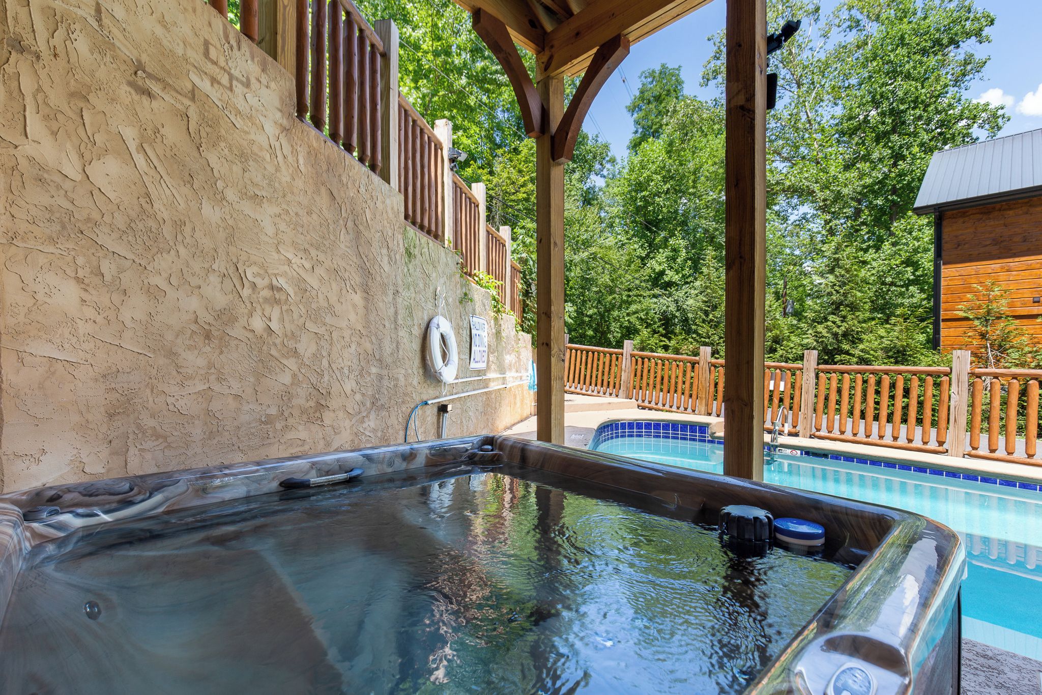 Un espace avec un jacuzzi, une terrasse en bois et une piscine en arrière-plan.