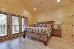 Un dormitorio con una cama de madera, dos mesitas de noche con lámparas y un ventanal con persianas.