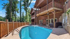 Une cabane en bois avec une piscine, un balcon et une vue sur les arbres.