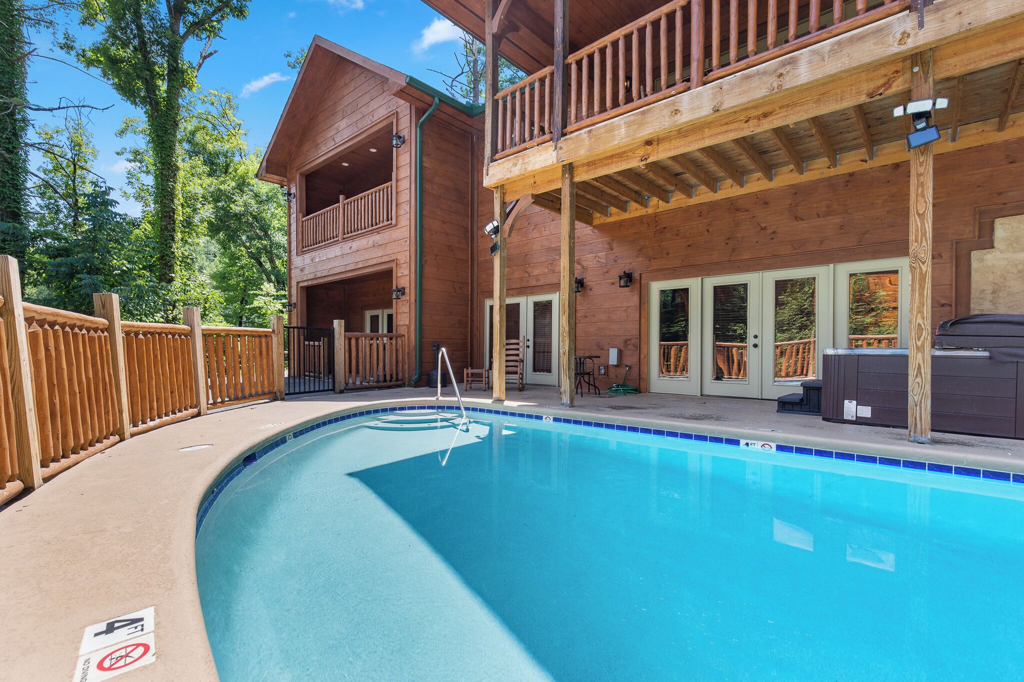 Une cabane en bois avec une piscine, un balcon et une terrasse.