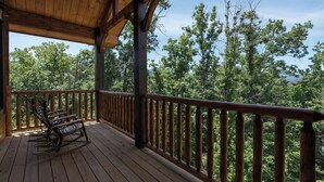 A wooden deck with a railing and a rocking chair. - Smoky Haven by Jackson Mountain Rentals (Gatlinburg)