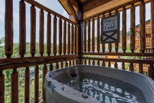 Una terraza de madera con un jacuzzi y un letrero que dice 'Pasa y siéntate un rato'.