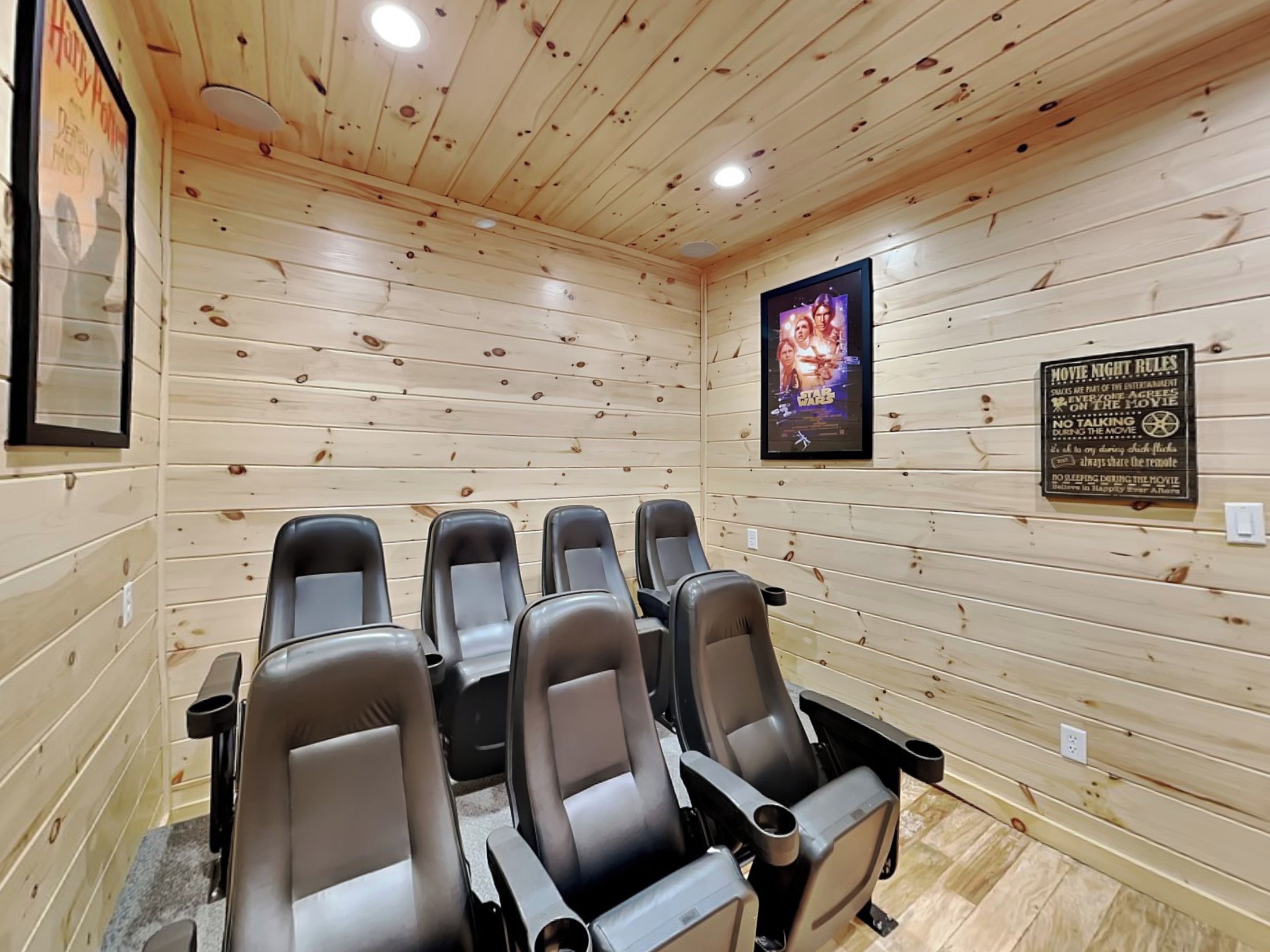 Ein Zimmer mit Holzwänden und sechs schwarzen Ledersessel, die in zwei Reihen angeordnet sind.