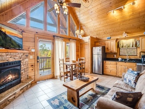 A cozy cabin interior with a stone fireplace, wooden dining table, and a sofa.