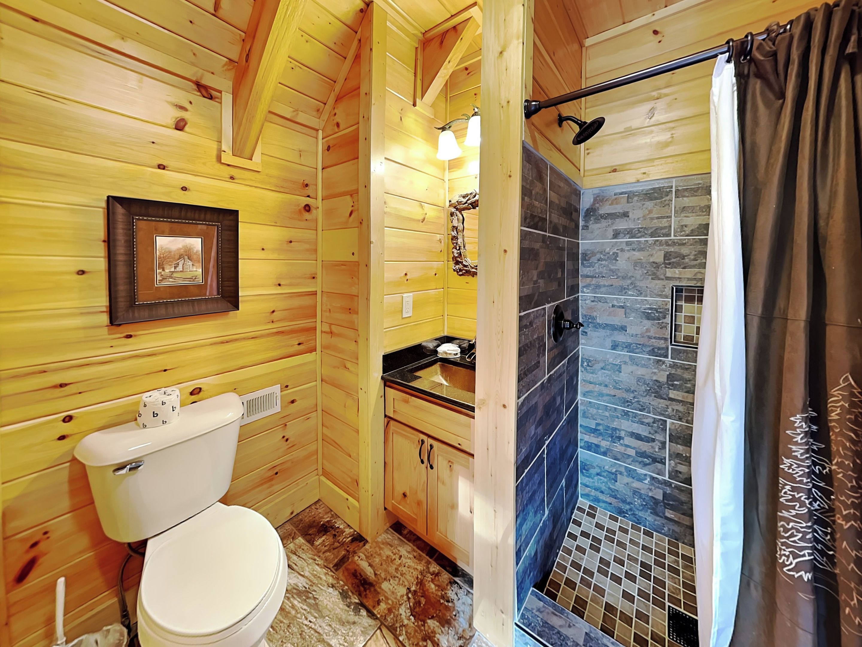 A wooden cabin bathroom with a toilet, sink, and shower area.