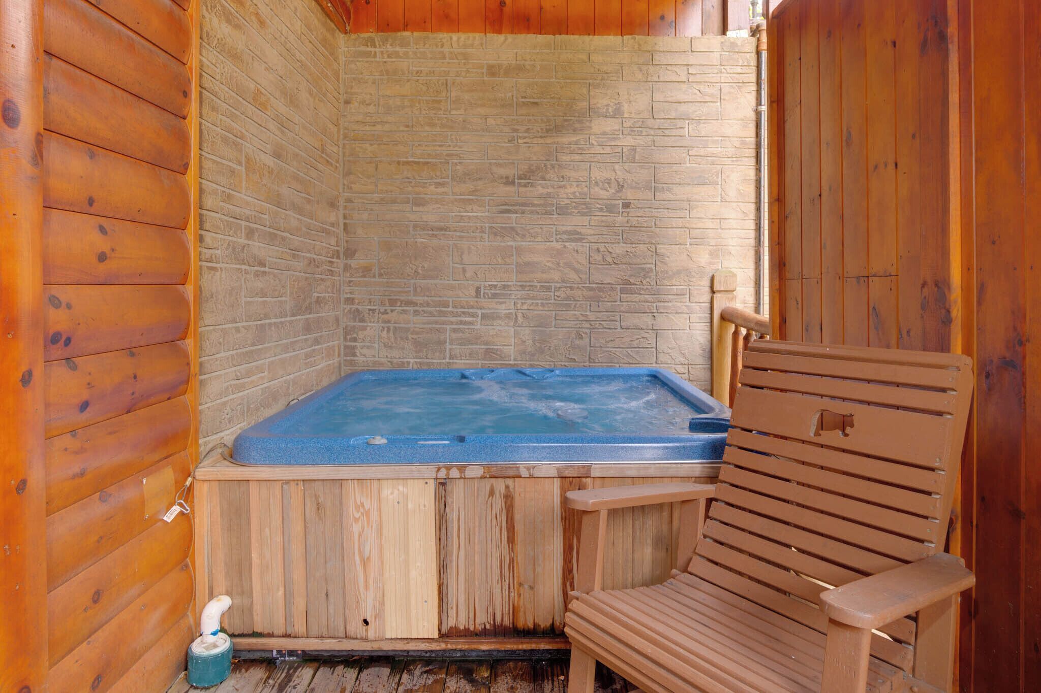 A wooden cabin with a hot tub and a wooden chair.