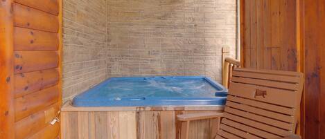 A wooden cabin with a hot tub and a wooden chair.