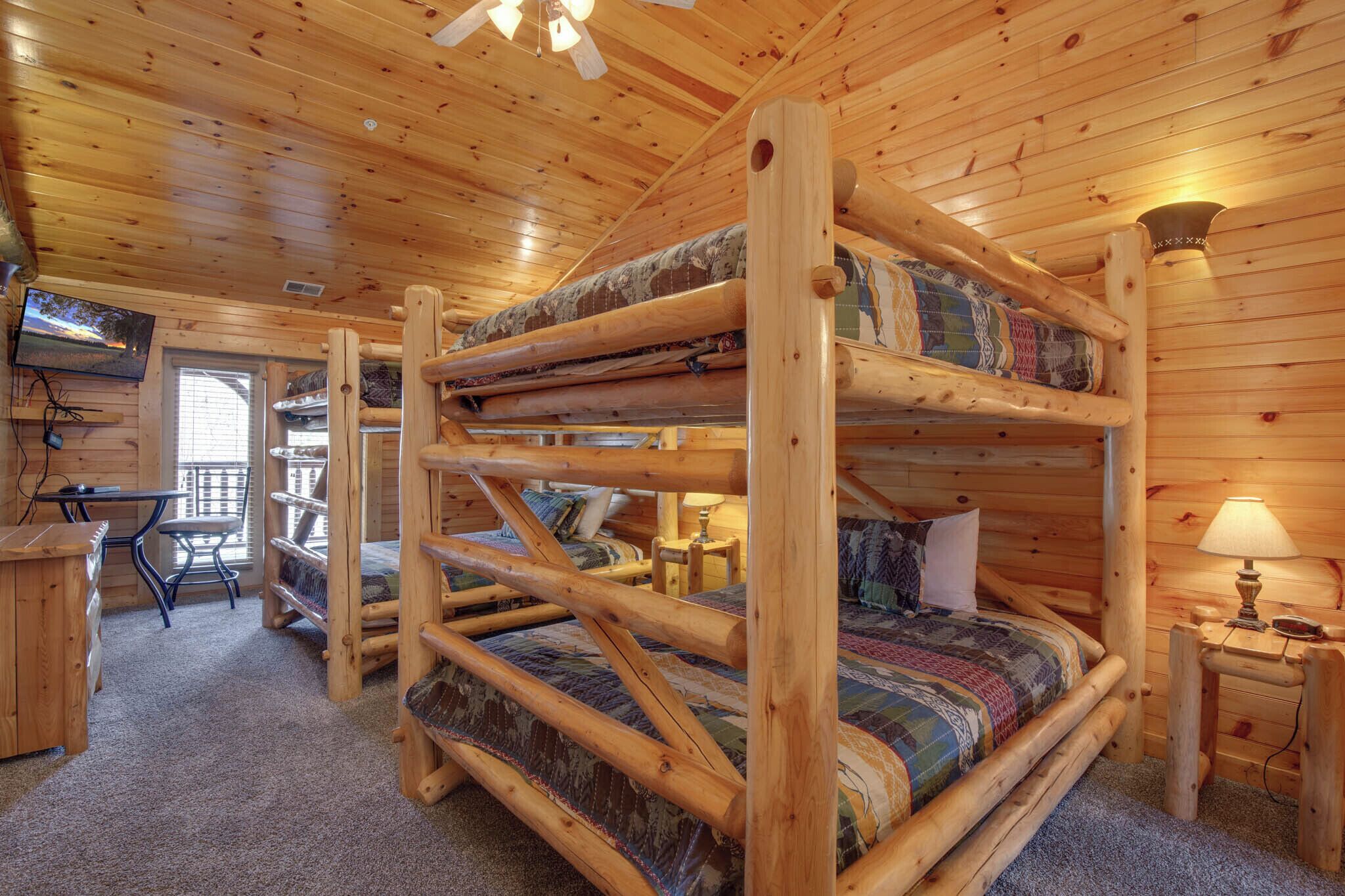 Una cabaña con una cama individual, un escritorio, una silla y un televisor.
