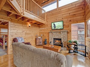 A cozy cabin interior with a wooden interior, a fireplace, a television mounted on the wall, and a comfortable seating area. - Picture Perfect by Jackson Mountain Rentals (Sevierville)