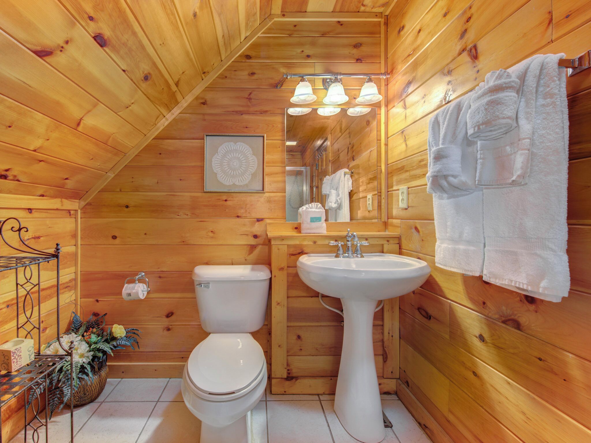 Un baño de cabaña de madera con inodoro, lavabo y espejo.
