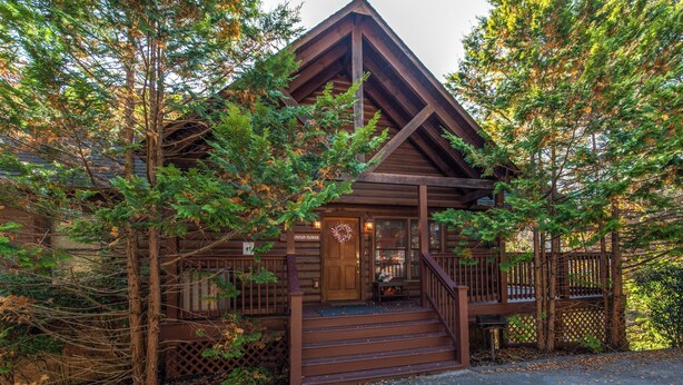 A rustic cabin with a wooden exterior, a porch, and a staircase leading to the entrance. - Mountain Flower by Jackson Mountain Rentals (Pigeon Forge)
