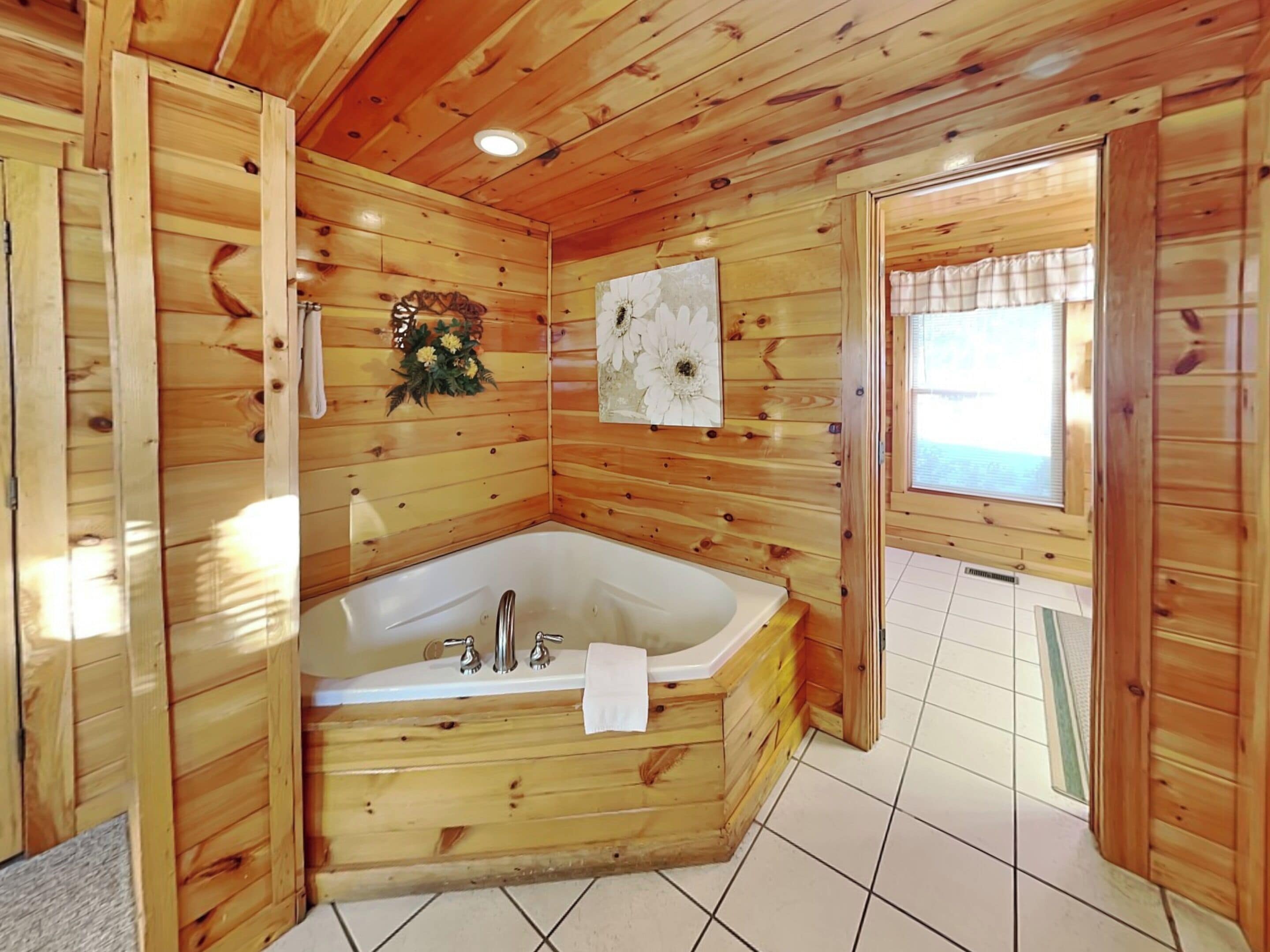 Eine Holzhütte mit einer Eckbadewanne, Holzvertäfelung und einem Fenster.