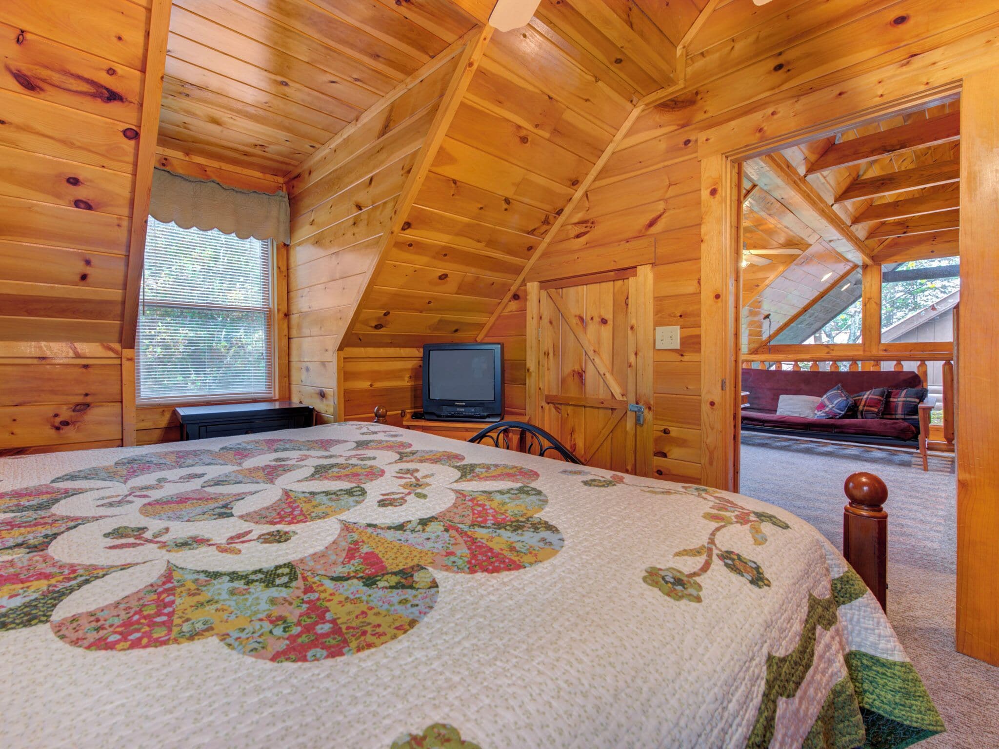 Une chambre confortable située sous les combles, avec un grand lit, une télévision et un plafond en bois.