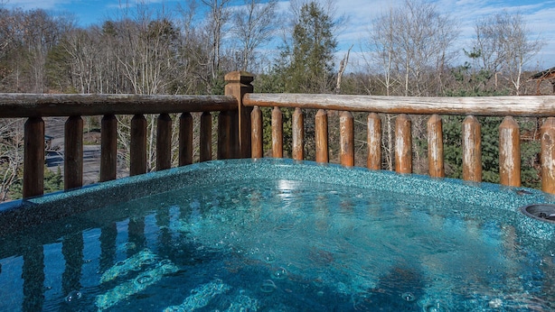 A hot tub with a wooden deck and a clear blue sky in the background. - Mountain View Lodge by Jackson Mountain Rentals (Gatlinburg)