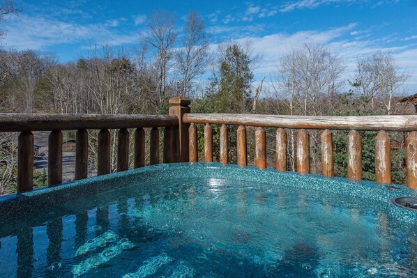A hot tub with a wooden deck and a clear blue sky in the background.