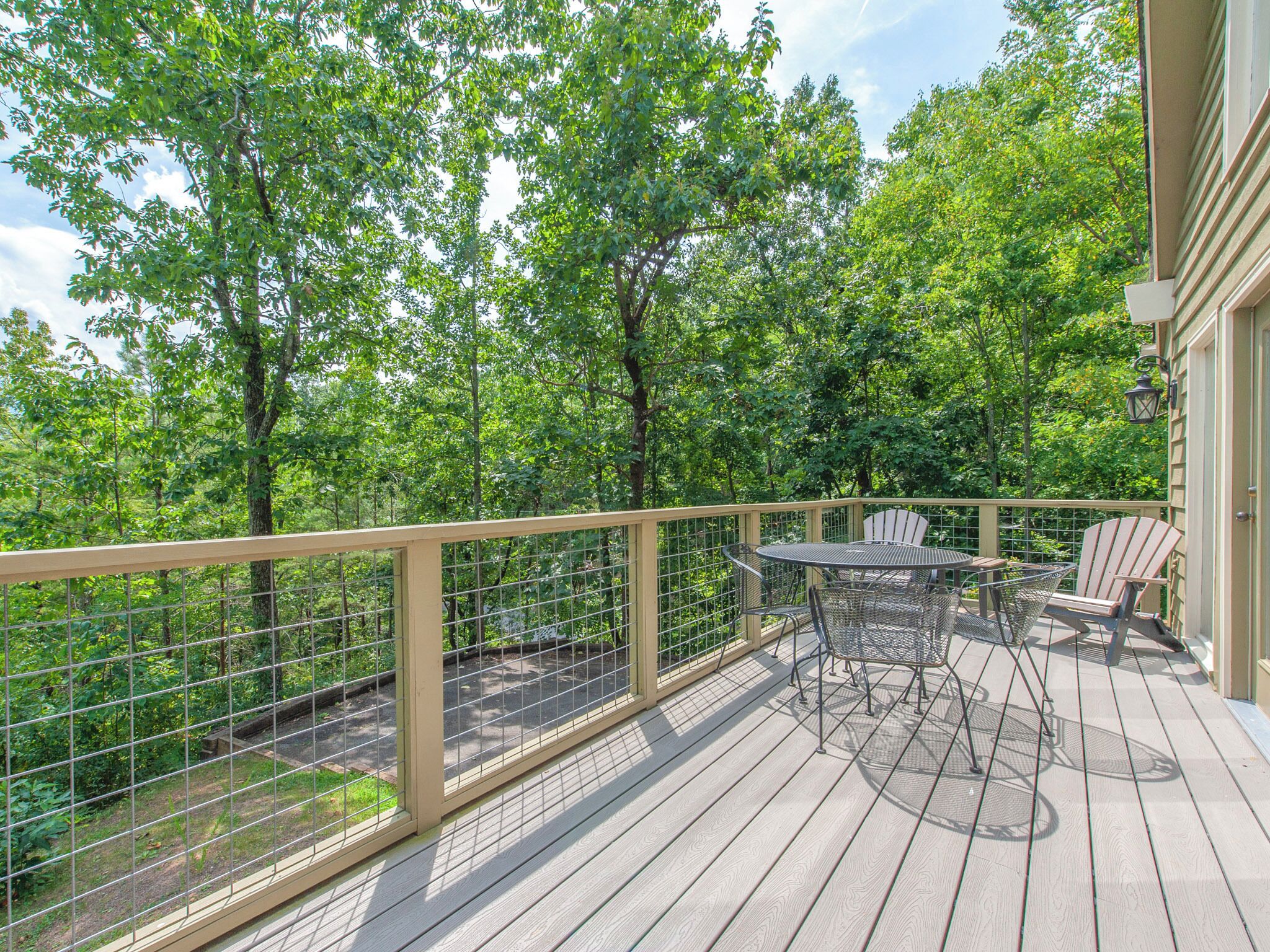 A wooden deck with a metal railing, a table, and two chairs.
