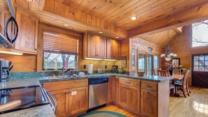 A spacious kitchen with wooden cabinets, granite countertops, and a built-in dishwasher. - Mountain Treasure by Jackson Mountain Rentals (Gatlinburg)
