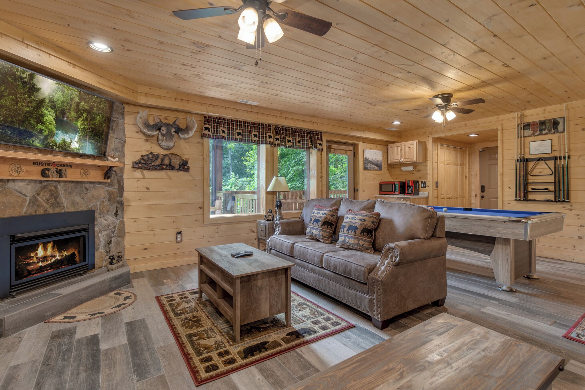 A cozy cabin interior with a fireplace, a pool table, and a comfortable seating area.