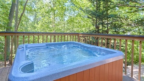 Een hottub op een houten terras, omgeven door bomen.
