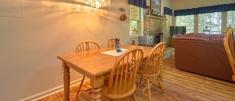 Un comedor con una mesa y sillas de madera, una araña y una chimenea de piedra.