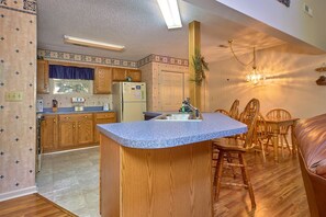 Une cuisine compacte dotée de meubles en bois, d’un plan de travail en granit et d’un coin repas avec des chaises et une table en bois.