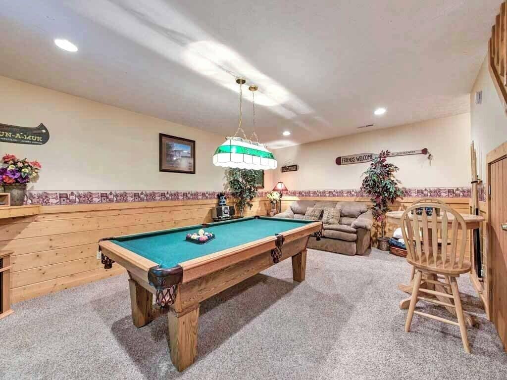 A pool table in a room with a wooden bench, a chair, and a sign that reads "Friends Welcome".