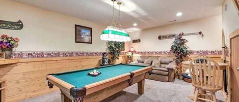 A pool table in a room with a wooden bench, a chair, and a sign that reads "Friends Welcome".
