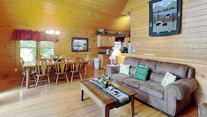 Ein Holzblockhaus im Inneren mit Essbereich, einer Couch und einer Küche.