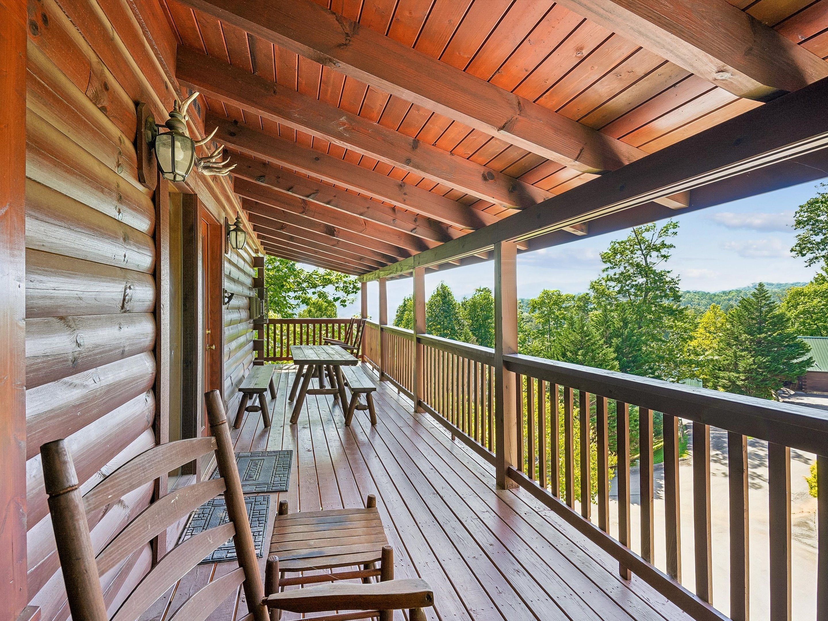 A wooden deck with a railing, a table, and chairs.