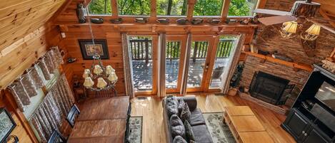 A cozy cabin interior with a dining area, sofa, and fireplace.