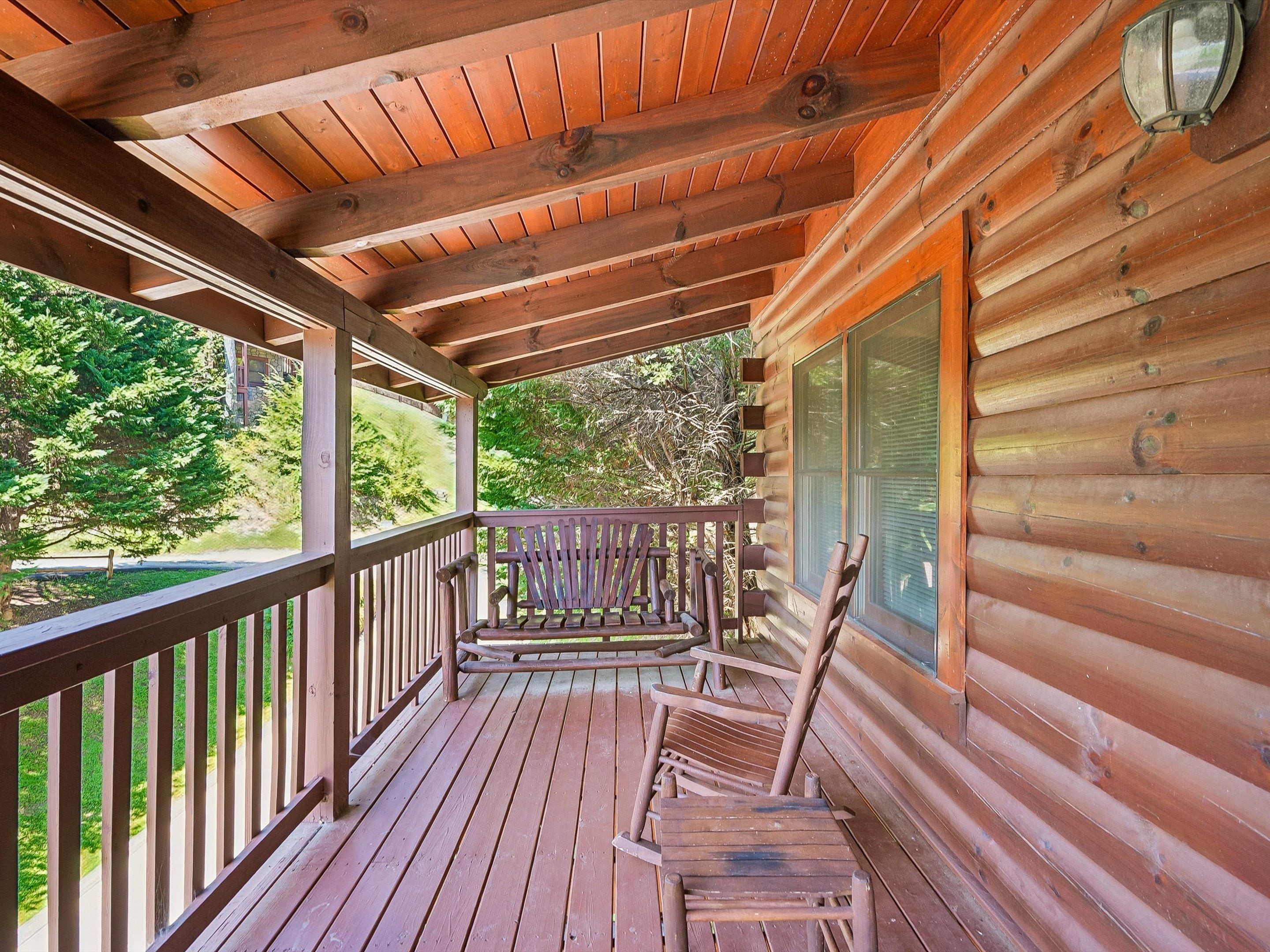 A wooden deck with a railing, a bench, and a window.