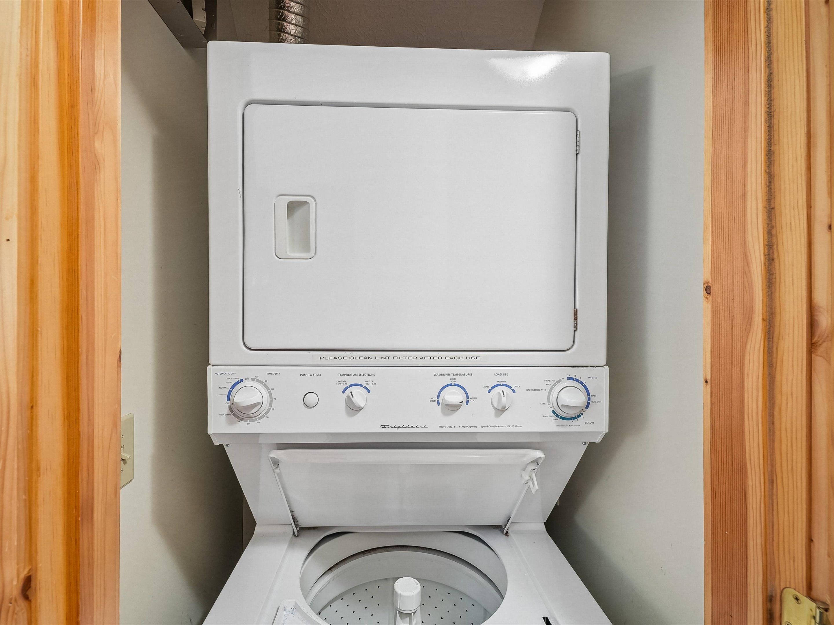 A white washing machine with a control panel, a lint filter, and a circular drum.