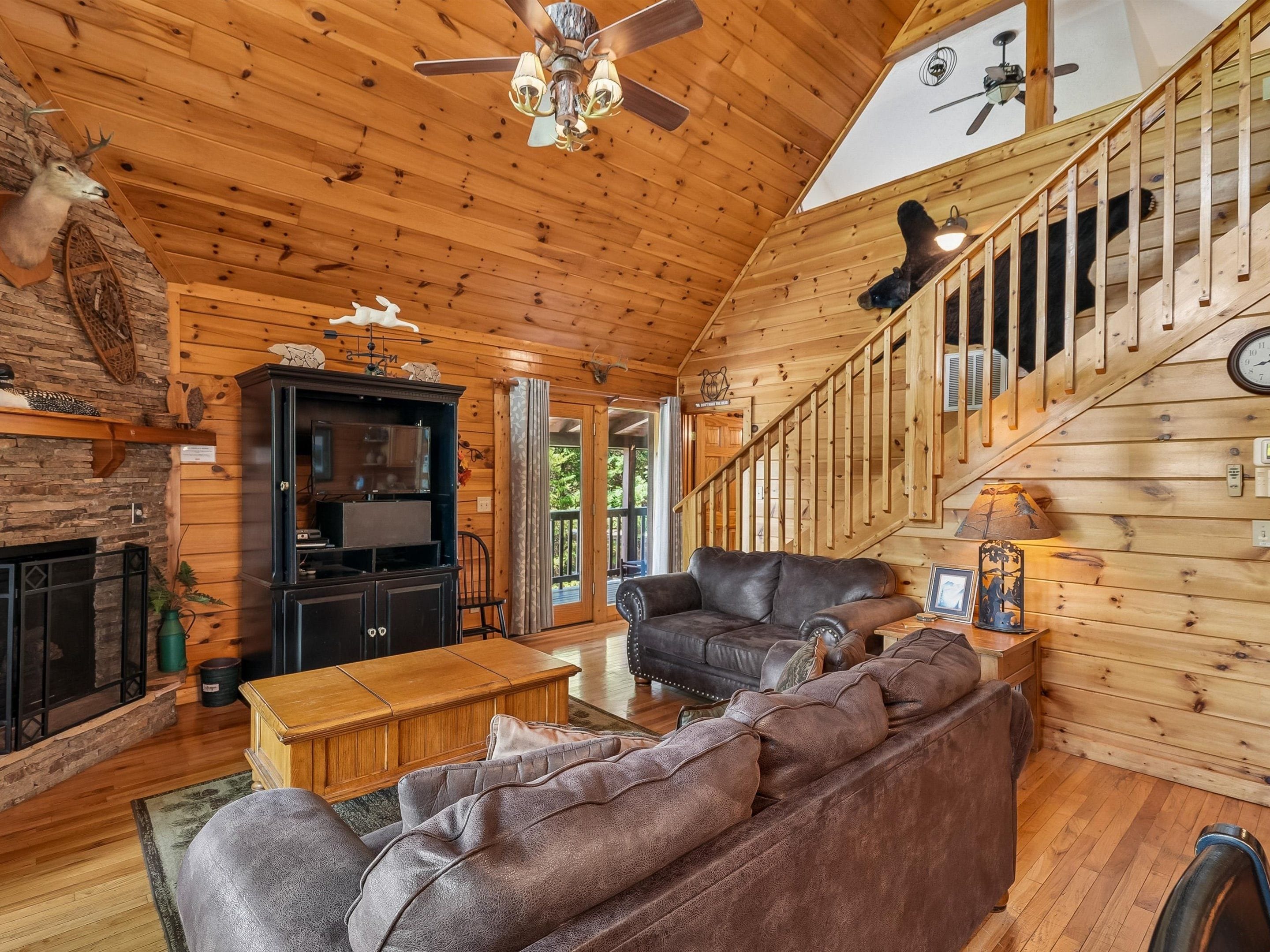 A wooden interior with a fireplace, leather sofa, and a staircase.