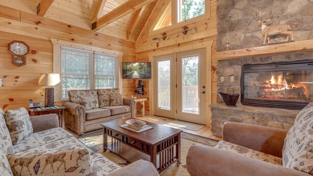 Un intérieur de chalet chaleureux avec une cheminée en pierre, des murs en bois et un coin salon confortable.