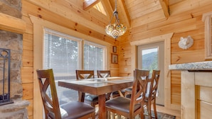 Un intérieur en bois avec une table et des chaises, un lustre et une cheminée en pierre.