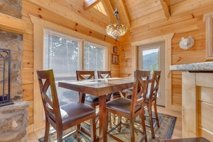Un interior de madera con una mesa de comedor y sillas, un candelabro y una chimenea de piedra.