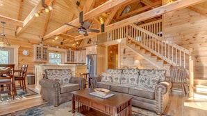 Un intérieur spacieux de chalet en bois, comprenant un salon, une cuisine et un escalier.