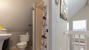 A bathroom with a toilet, sink, and shower curtain. - Kickback Kabin by Jackson Mountain Rentals (Gatlinburg)