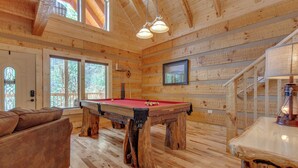 A wooden interior with a pool table, a sofa, and a staircase. - Lover's Hideaway by Jackson Mountain Rentals (Gatlinburg)